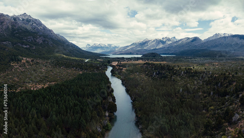 Aerial view of a tranquil river winding through a lush Patagonian valley, flanked by dense forests and the majestic Andes in the background photo