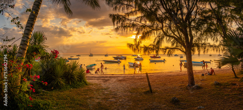 View of boats and people on Mon Choisy Public Beach at sunset, Mauritius photo