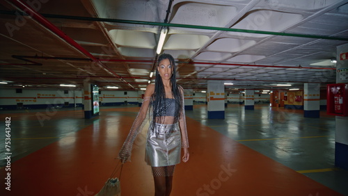 Relaxed brunette crossing underground parking posing at night alone portrait