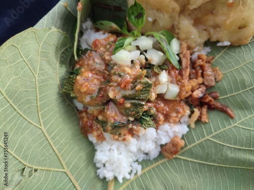 Nasi pecel or sega pecel is a typical Javanese Indonesian rice dish served with pecel. dish is usually made from water spinach, long beans, mixed with peanut sauce. photo