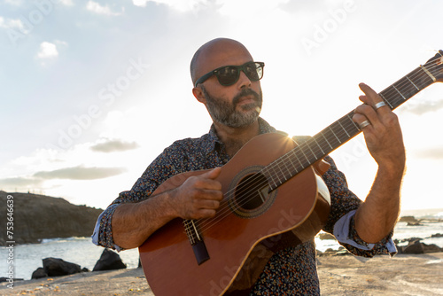 Man playing guitar by the sea at sunset photo