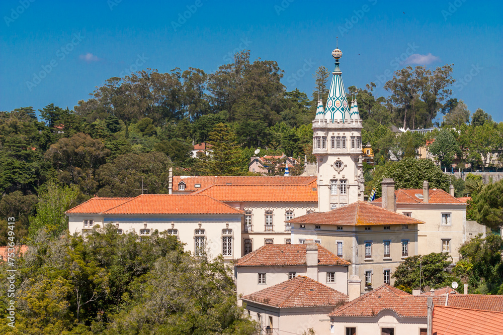 View of the beautiful town hall of Sintra, Portugal. The City Hall building showcases a delightful clock tower with spired roof, green and white tiles and the Portuguese Coat of Arms.