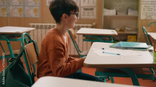 Child kid son pupil student bad behavior boy schoolboy playing video game on mobile phone at lesson at school hide smartphone under class desk distract from studying gadget addiction writing learning