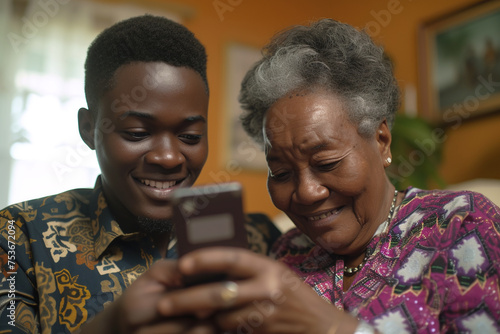 young african man helping senior grandmother relative to use smartphone. teaching elders technology, grandparent using gadgets indoors