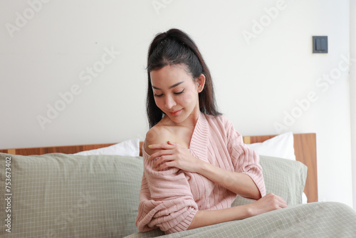 Woman in Bed Inspecting Her Shoulder in Morning Light