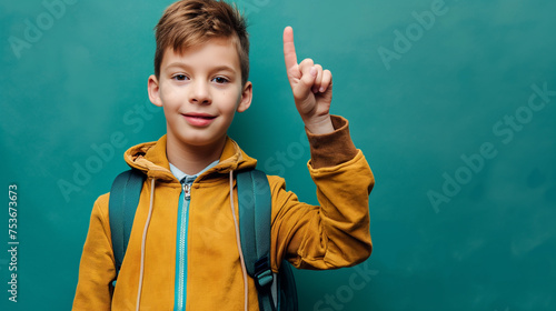 Garoto com mochila pronto para ir a escola levantando o braço isolado no fundo azul photo