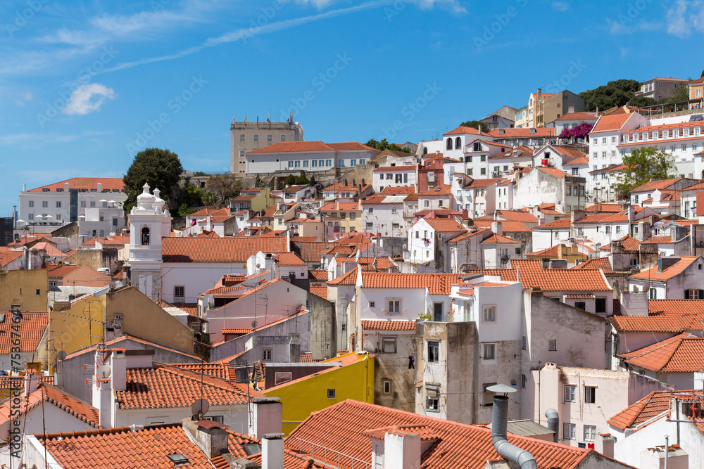 Cityscape  of traditional white houses, orange rooftops and blue sky in Lisbon historic center, Portuguese balconies, construction and antennas, Portugal