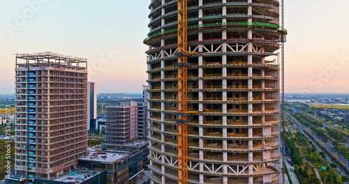 Aerial video of construction site at sunset. High rise buildings in construction site. Unfinished building scene. Drone surround shooting. photo