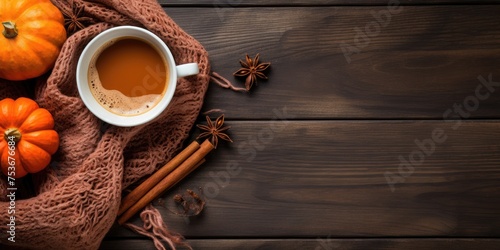 Hot autumn drink on scarf with pumpkins and spices on wooden table. Top view with rustic background and copy space.