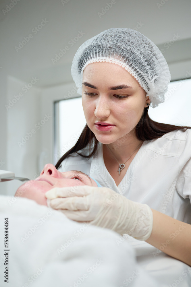 Close up of ultrasound skin cleaning and facial peeling procedure in beauty clinic. Macro shot of woman under procedure of ultrasonic facial. Deep pore cleansing treatment Close up of ultrasound skin cleaning and facial peeling procedure in beauty clinic. Macro shot of woman under procedure of ultrasonic facial. Deep pore cleansing treatment