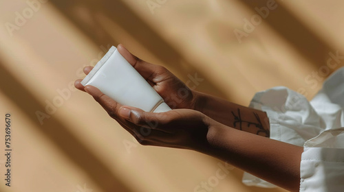 woman hands holding blank cream tube on light brown background, skincare concept, beauty concept
