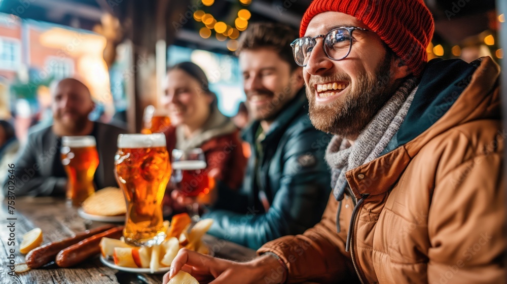 A group of friends in winter clothes drink beer and have fun on the terrace of a bar