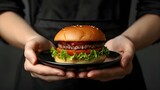 Hands holding tasty beef burger on black background