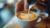 Close-up of a barista pouring milk into a coffee cup creating latte art