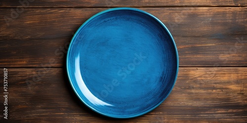Blue plate on wooden background with empty space for design.