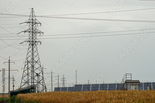 Power lines transmitting renewable energy from solar panels on farm. Distribution lines for transferring alternative form of energy for buildings