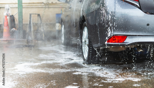 A sedan being thoroughly cleaned with water and soap at a car wash station..