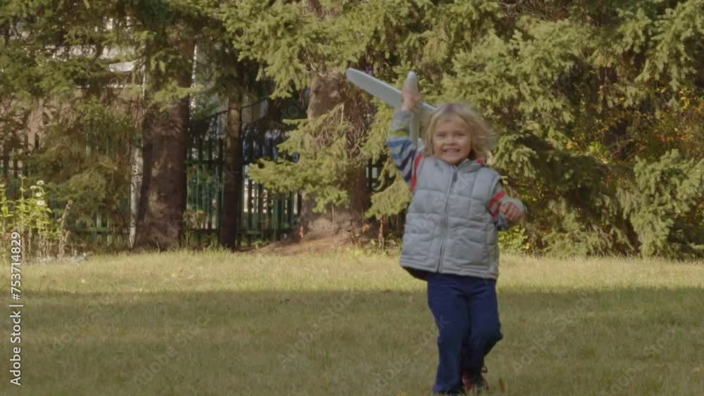 Happy child runs with a toy airplane in public park. Cheerful Little Boy Having Fun With toy plane. Slow motion. Happy child runs with a toy airplane in public park. Cheerful Little Boy Having Fun With toy plane. Slow motion.