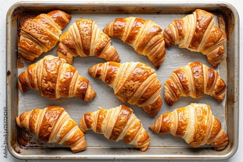 An overhead shot of a baking tray filled with golden brown croissants