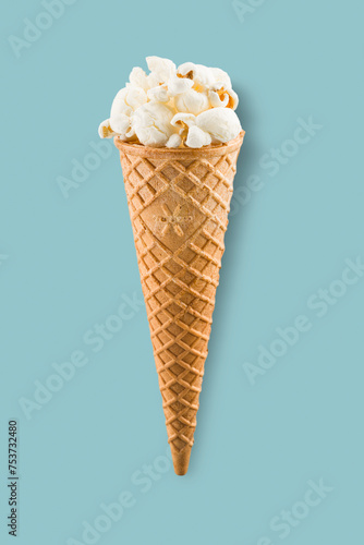 Popcorn in ice cream cone on blue background.