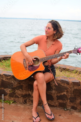 Mujer caucásica de nacionalidad argentina joven y hermosa tocando la guitarra en un paisaje