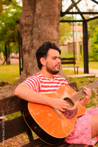 joven musico caucásico de nacional argentina tocando la guitarra al aire libre 