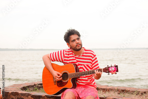 joven musico caucásico de nacional argentina tocando la guitarra al aire libre 
