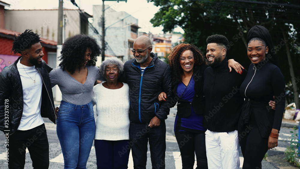 Group of Joyful Brazilian people smiling and laughing together standing in city street posing for camera. United Family of African descent embrace