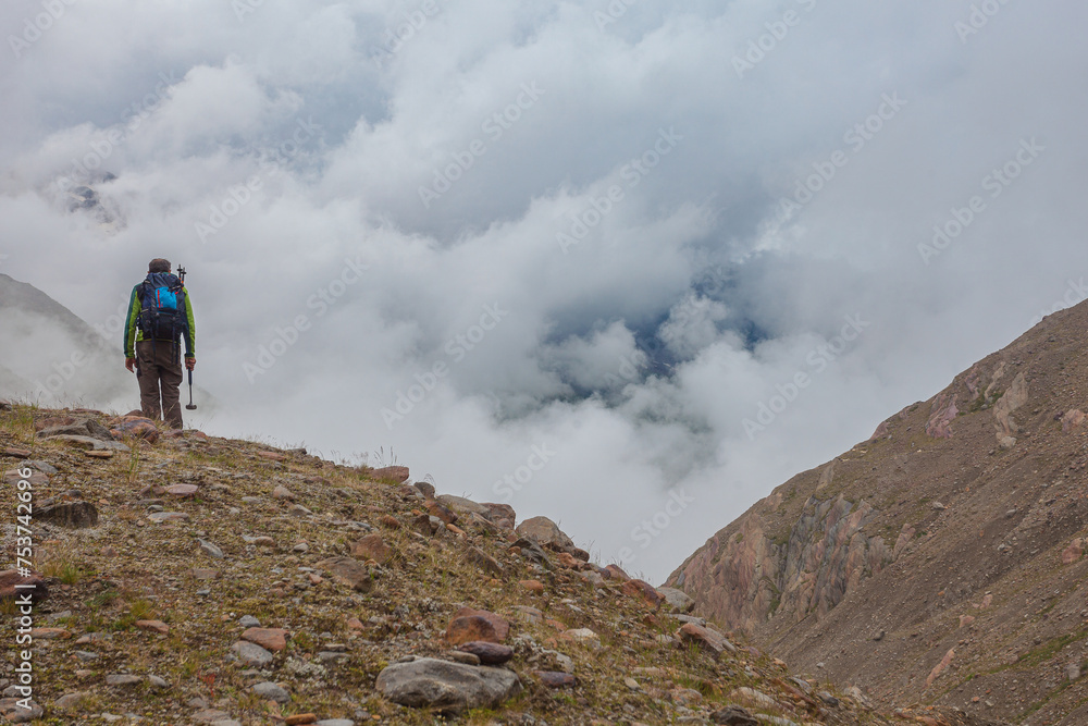 Fototapeta premium Alpine highlands countryside. Higher part of alpine valley in a cloudy day with unrecognizable mountaineer on ancient moraines . Vallelunga, Alto Adige Sudtirol, Italy