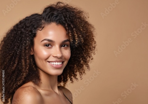 Beautiful smirking curly brunette american african woman with healthy skin looks at the camera. Natural makeup of a young beautiful model on a studio background. Cosmetic concept.