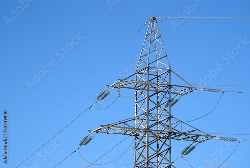 Top section of high-voltage power line metal prop on clear blue sky as background