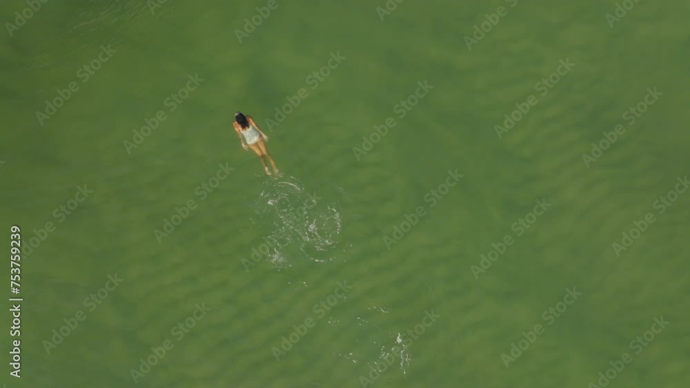 Drone View: Woman's Sunlit Swim in Tropical Waters Drone View: Woman's Sunlit Swim in Tropical Waters