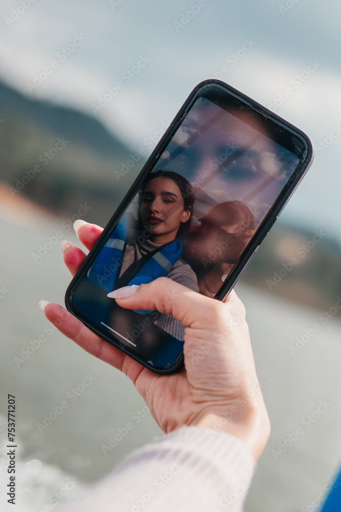 A woman is holding a cell phone up to her face, taking a selfie. Concept of self-expression and confidence, as the woman is capturing her own image in a moment of her day