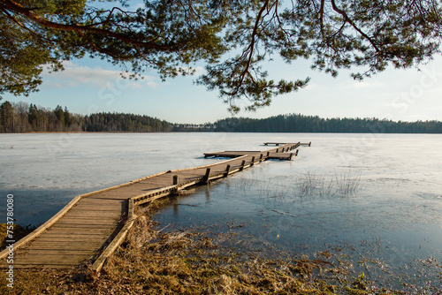 Canvas-taulu Wooden footbridge in Ratnieku frozen lake in early spring in March in Ratnieki i