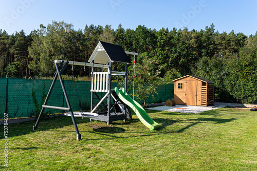 A childrens playground made of wood and painted white and navy blue, standing in the garden.