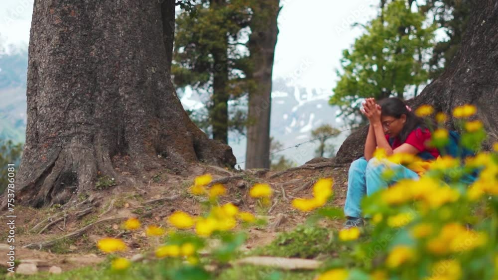 Defocused shot of tired hiker girl resting under tree with flowers in ...
