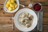 Königsberger Klopse mit Kapern, Salzkartoffeln und Rote Beete Salat auf tiefer Teller und rustikalen Holztisch mit Besteck, Salz und Serviette