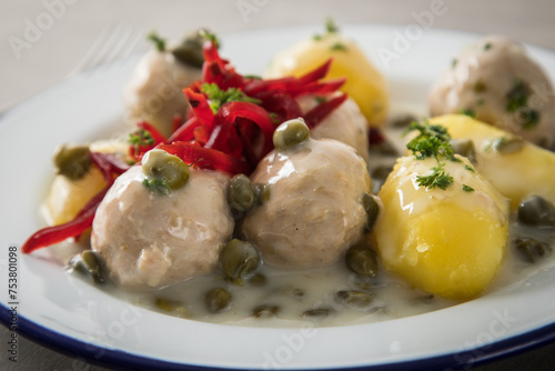 Königsberger Klopse mit Kapern, Salzkartoffeln und Rote Beete Salat auf rustikal Emaille Teller und grauen Stein Hintergrund mit Besteck