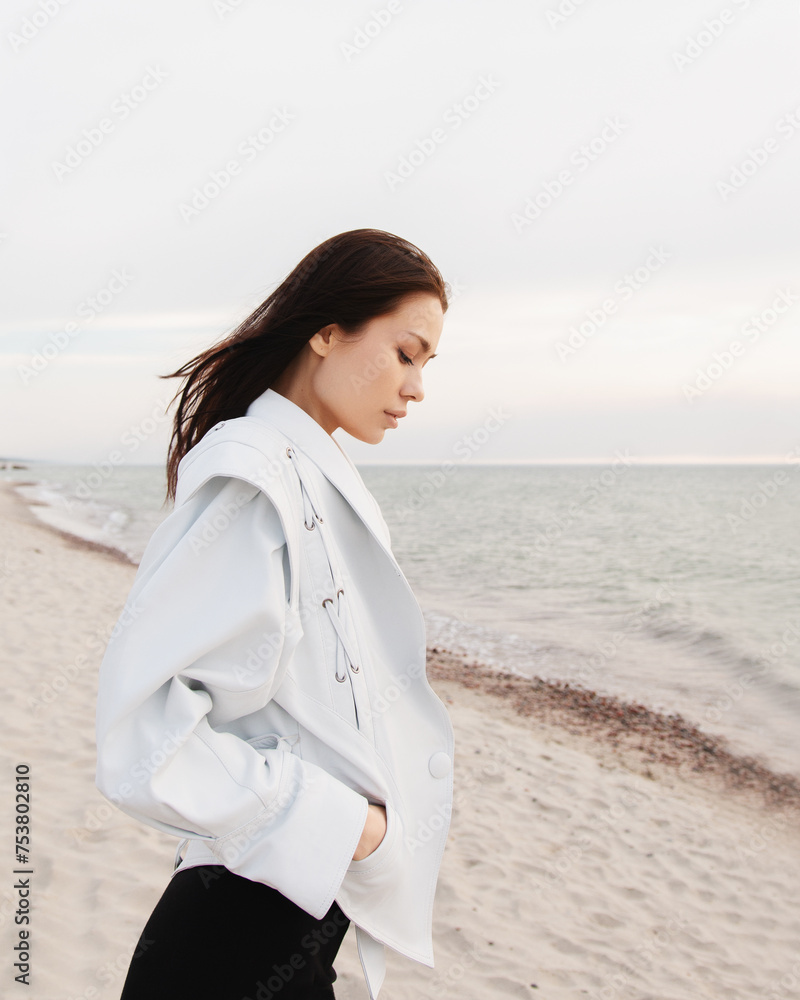 A girl in white jacket standing on the sea background in golden hour. A girl in white jacket standing on the sea background in golden hour.