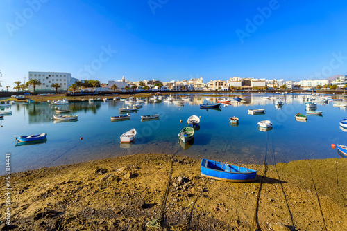 Colorful small fishing boats float in the Charco de San Gines seawater lagoon at the seaside Spanish town of Arrecife, Spain, on Lanzarote Island, one of the Canary Islands in the Atlantic Ocean. photo