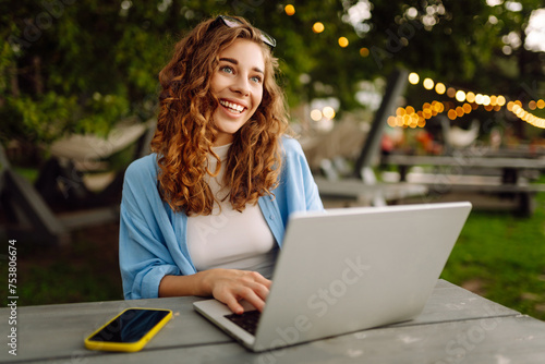 Young woman working outdoors enjoying the good weather. Freelance, technology, education, business, blogging concept.