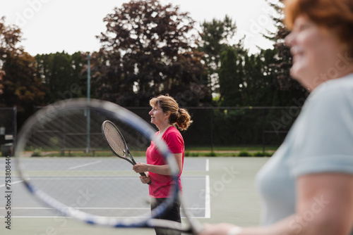 Two women waiting and ready to play tennis on the court in the s photo