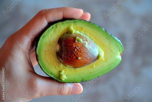 A hand tenderly holding a perfectly ripe avocado, its green, creamy texture just visible from a neatly cut half, set
