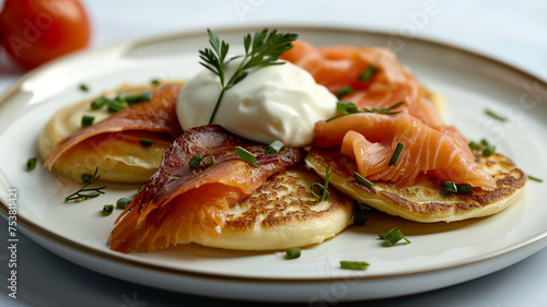 A plate of delicate blini, topped with smoked salmon and a dollop of sour cream, arranged on a white background to capture the elegance of this traditional dish