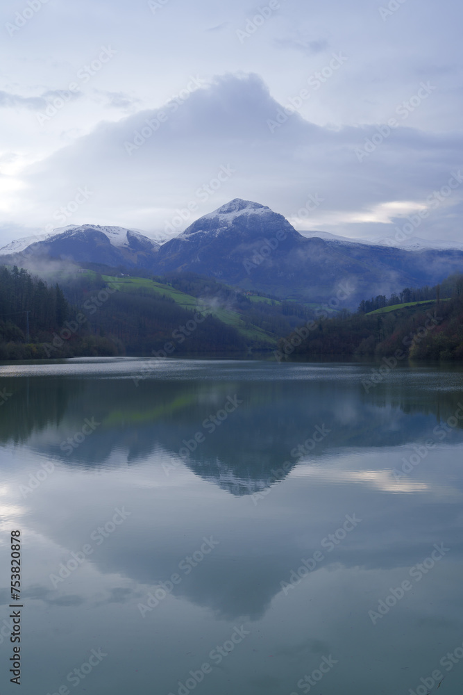 Txindoki with snow. Mount Txindoki reflected in the Ibiur reservoir, Basque Country.