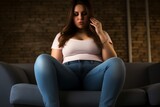 Chubby Woman with love handles wearing a Tank top and jeans sitting on a couch