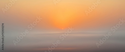 Abstract summer background with orange evening sky and fog below in the valley