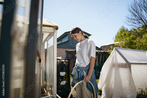 A woman pours water through a hose photo