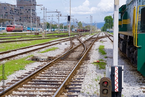 Canvastavla Railway station of Ljubljana with railway tracks and switches and parked green shunting diesel locomotive on a cloudy summer day