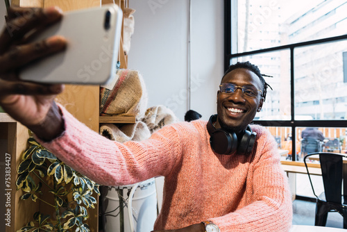 Cheerful black man taking selfie in cafe photo